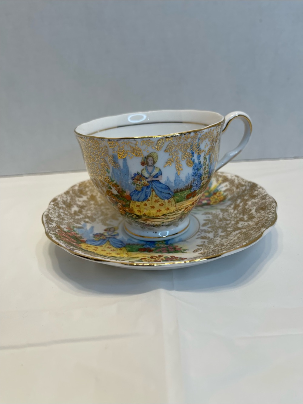 Gold-Trim Porcelain Teacup and Saucer with Pastoral Scene in Blue and Yellow